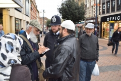 Rashid Laher, the secretary of the South London Interfaith Group shares contact details with a police officer outside the Bentall shopping centre in Kingston during a vigil for the victims of the Westminster attack