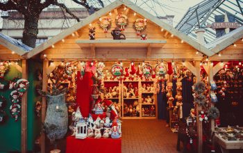 A wooden Christmas market stall displaying a variety of Christmas decorations, such as wreaths, Christmas elf soft toys and reindeers figurines.