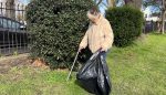 Woman picking up litter in a park with a trashbag and picker