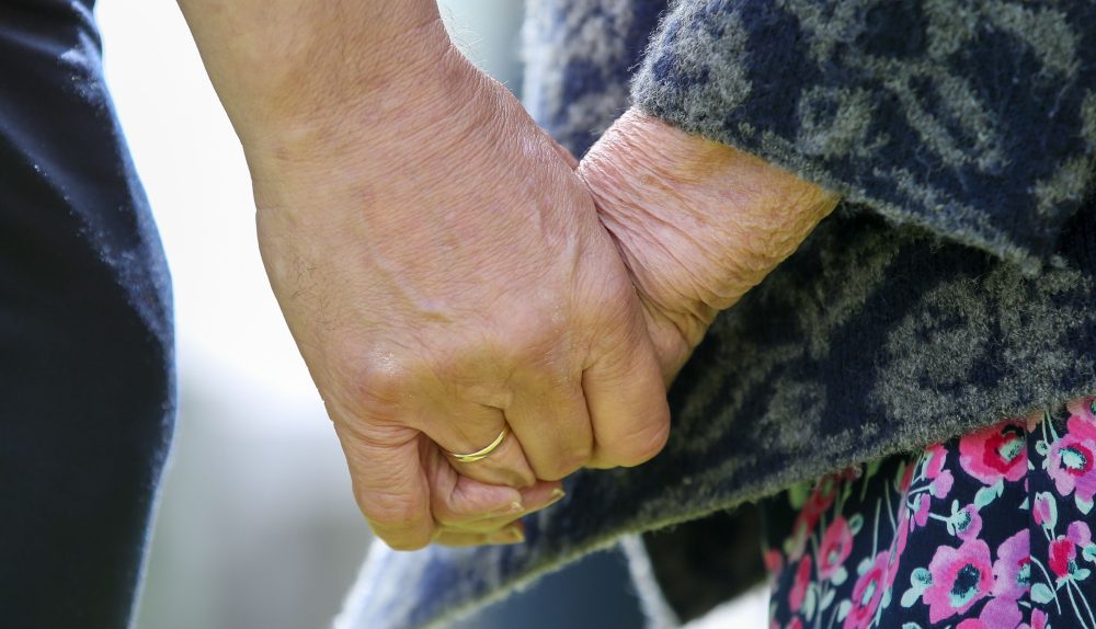 Ed Davey holding the hand of a resident at Abbotswood Court Care village.