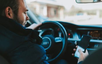 A man driving a car while using his mobile phone.