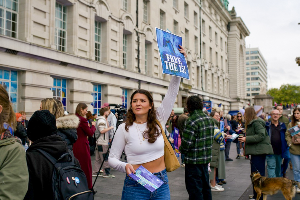 A woman holds up her “free the 15” sign and passes out flyers to passerbys during the protest. Photographer: Sky Allen/Kingston Courier